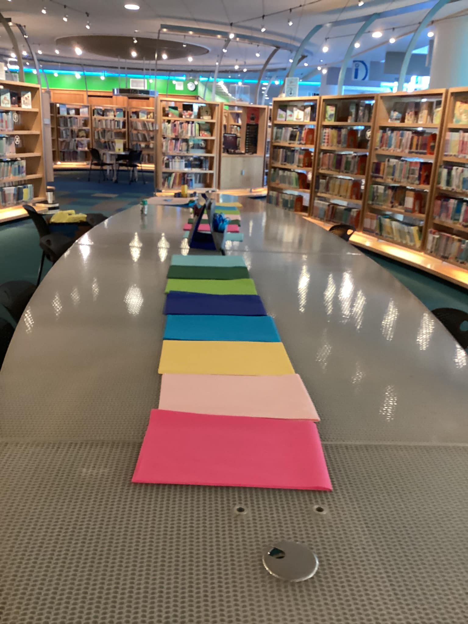 Table surrounded by shelves of books with squares of colored material spread out