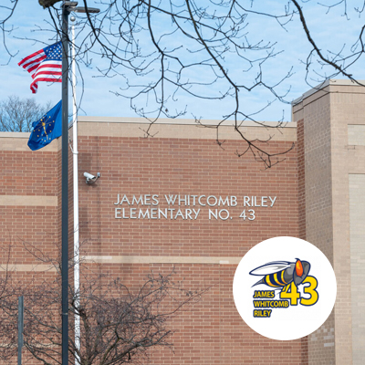 Photo of the exterior of the school with the logo inset in a white circle. Logo has an illustration of a hornet and the words James Whitcomb Riley and 43 in yellow